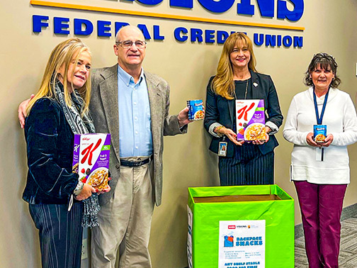 Visions employees Liz, Shari, and Gloria stand smiling with radio personality Steve Andrews, as they all show off collected food items for Backpack Snacks for Kids.