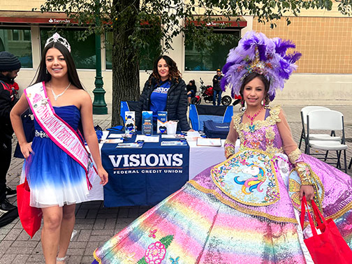 Two marchers from the Puerto Rico Pride Parade pose in front of the Visions Federal Credit Union table. 